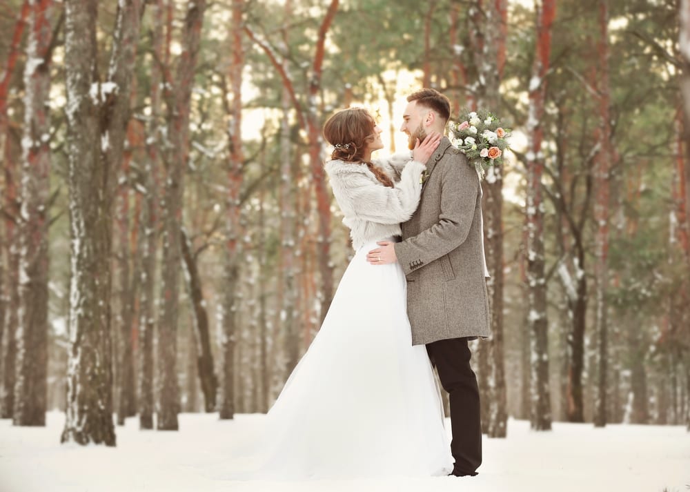 Bride and groom hugging in snowy winter forest