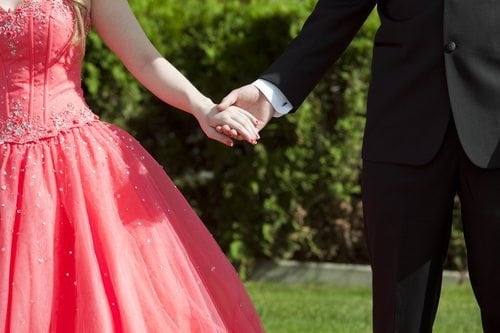 Close cropped outdoor photo of couple dressed in formalwear holding hands